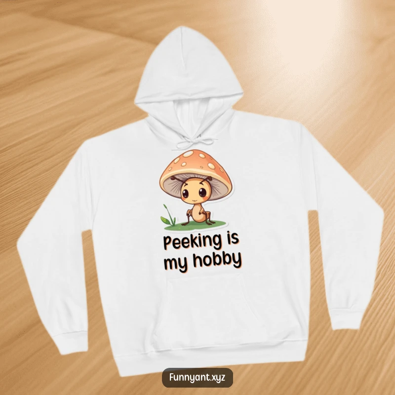 Funny hoodie depicting a cute ant character peeking curiously from under a mushroom cap, perfect for those who enjoy quiet observation.
