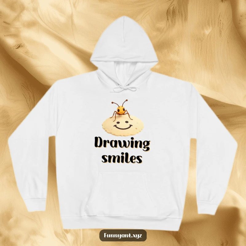 Funny hoodie featuring a tiny ant artistically drawing a smiley face in the sand, offering cozy and humorous creativity.
